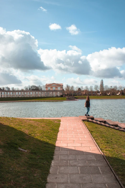 man on boardwalk near water with clouds in sky