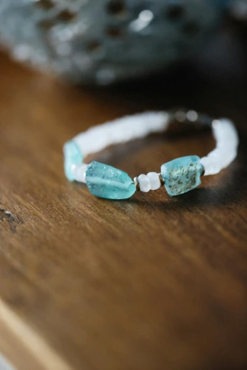 a turquoise celet with white beads sitting on a wooden table