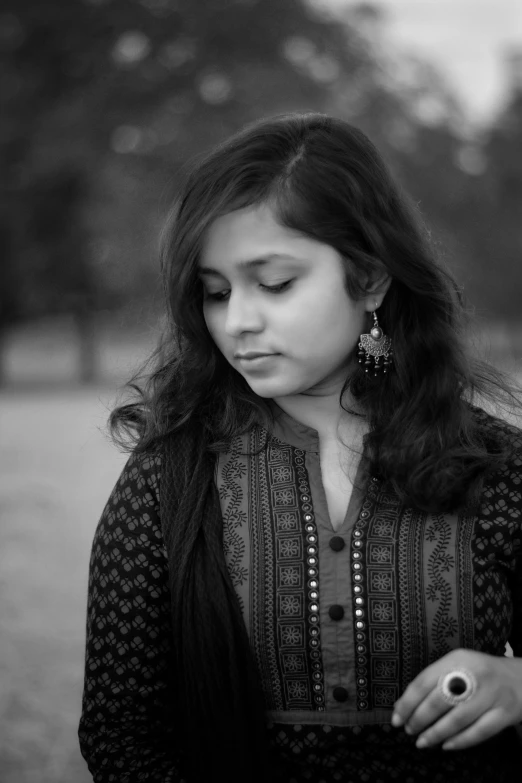 a woman in a black dress and necklace holding a cell phone