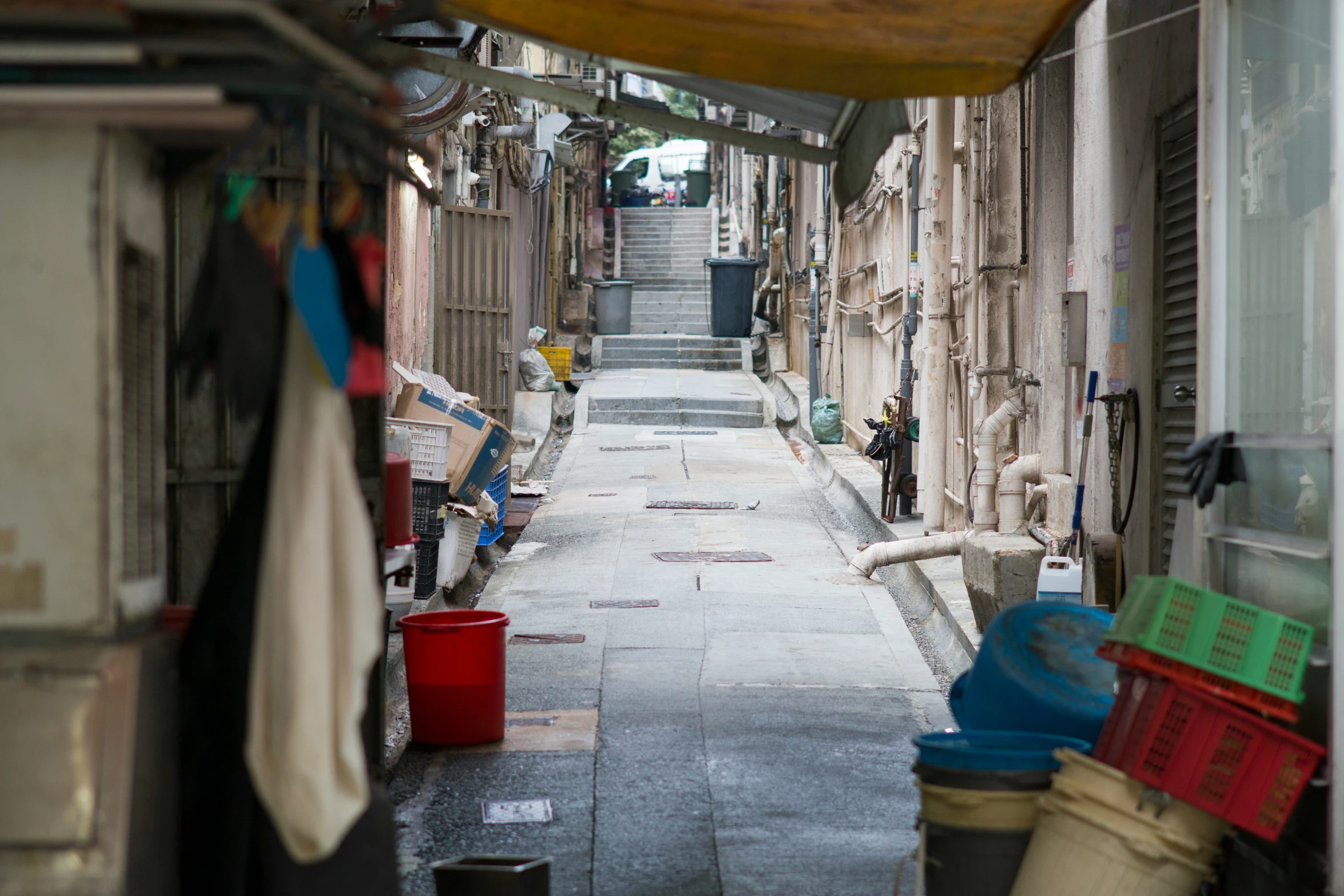 a narrow street has various laundry hanging from buildings