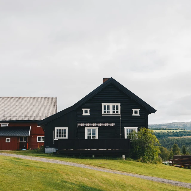 two black barns sitting on top of a lush green field