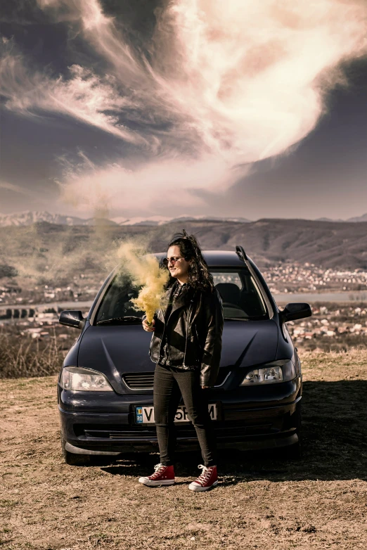 a young woman standing in front of a black car
