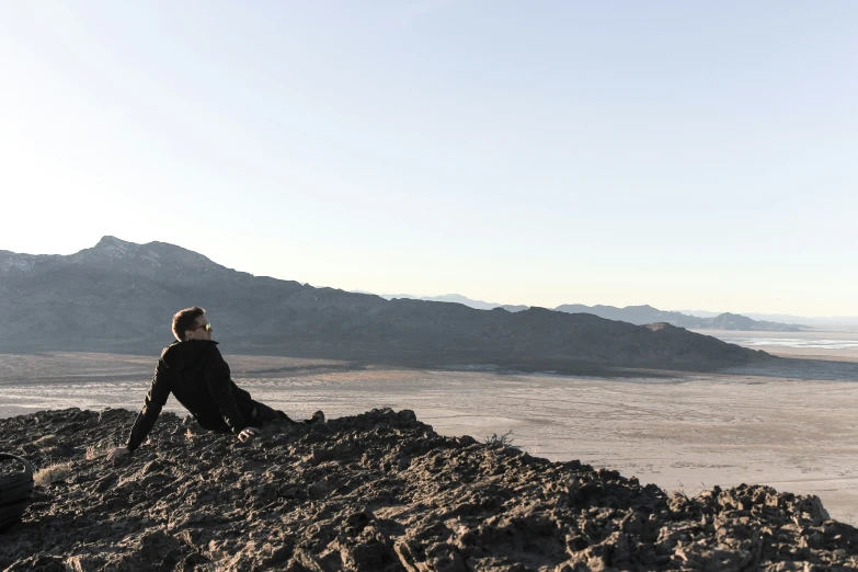 a man sits on top of rocky terrain as he looks over the mountains