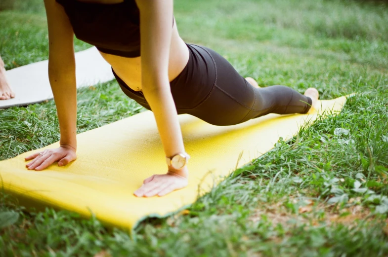 a woman is doing a yoga position on a yellow mat