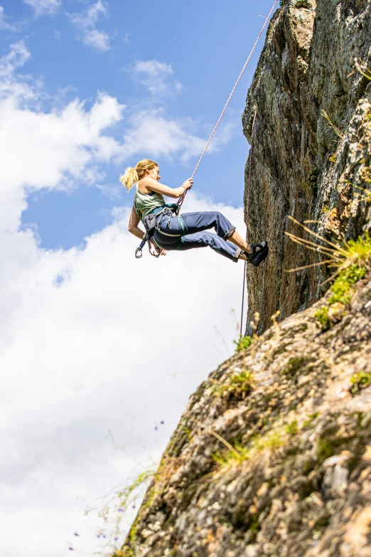 a woman is on a rock wall and holds onto her rope