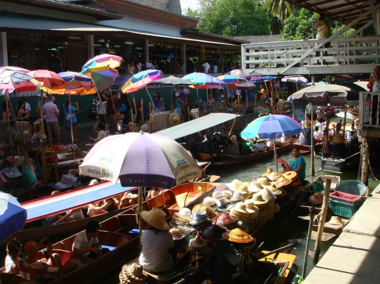 several boats with umbrellas and people standing near by