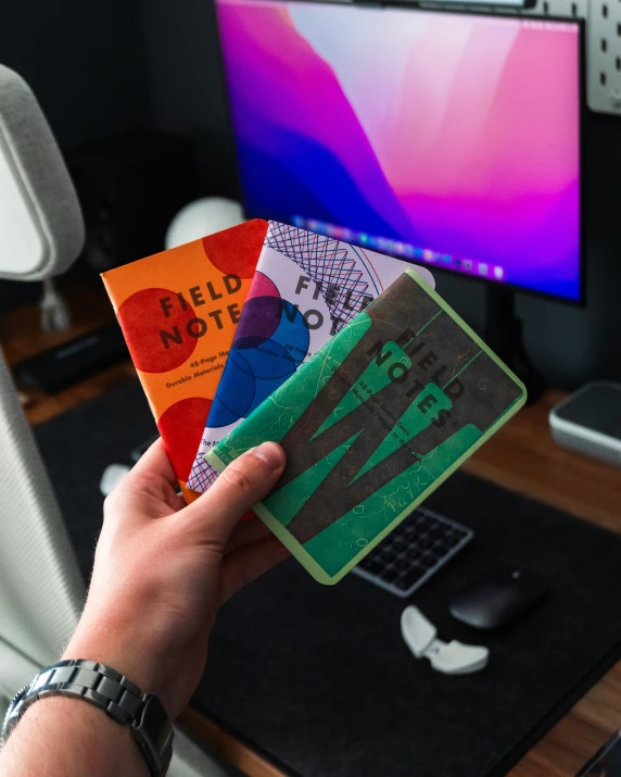 an individual's hand holding four books