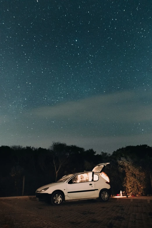 a small car parked in the middle of a field under a night sky full of stars