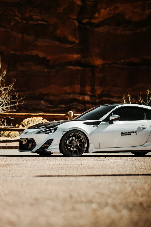 the sports car is parked in front of some cliffs