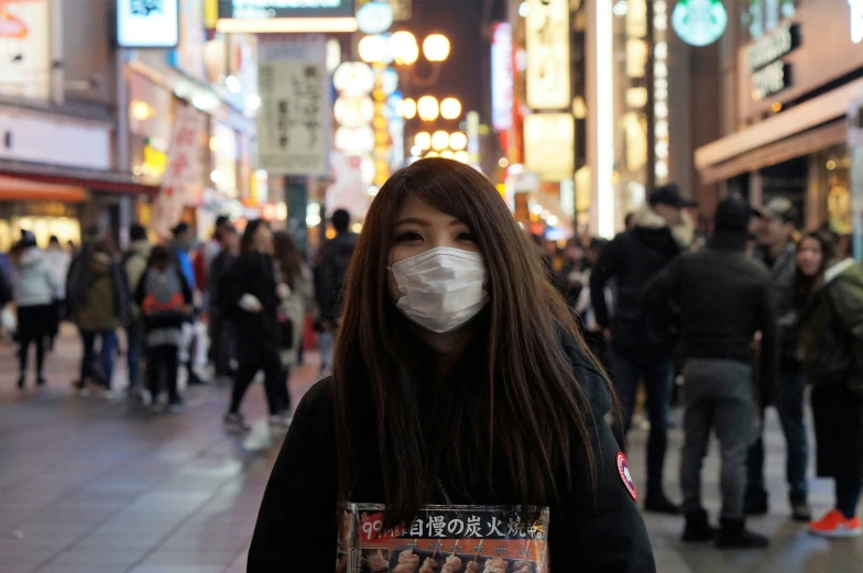 a woman is standing on a busy sidewalk in an asian city with signs and lights