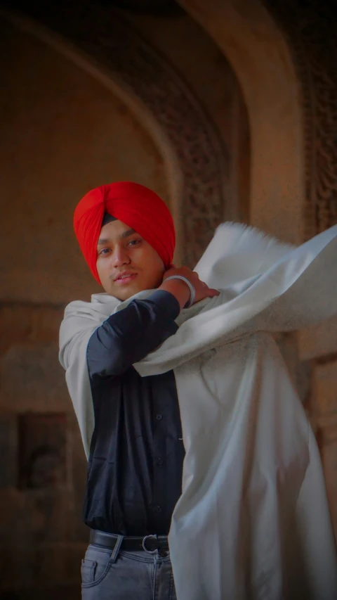 a young man wearing a turban and standing next to a stone wall