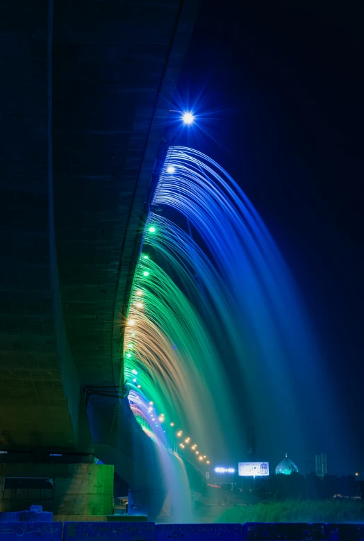 a view under a bridge at night, shows water and lights