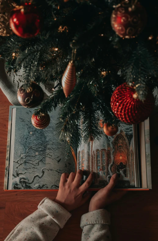 someone's hand touching the tree on a wood table
