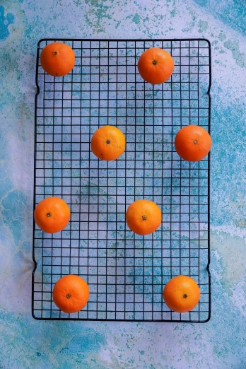 nine oranges on top of a wire rack on a blue background