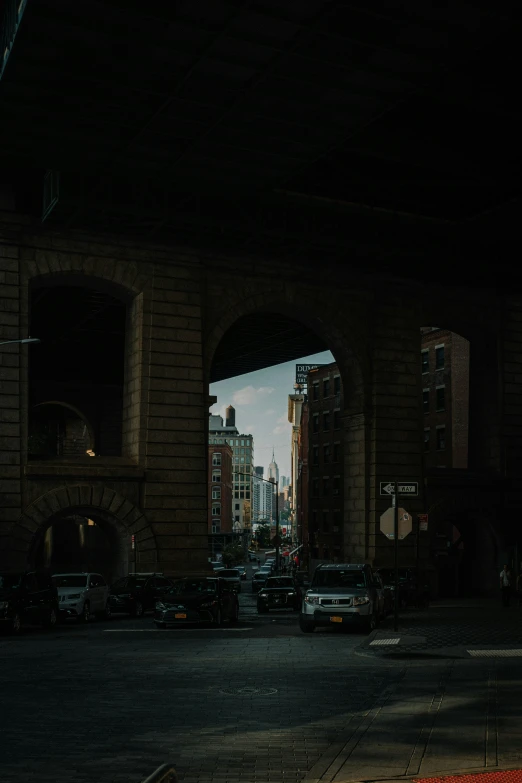 a dimly lit tunnel with cars coming from it and a skyline in the background