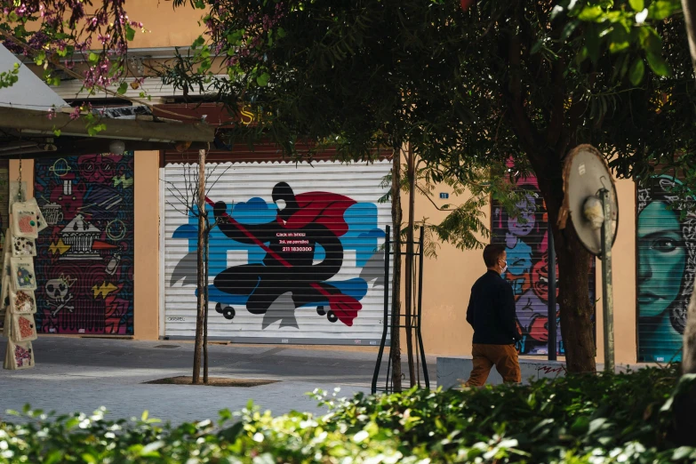 a man is walking down a street past a wall mural