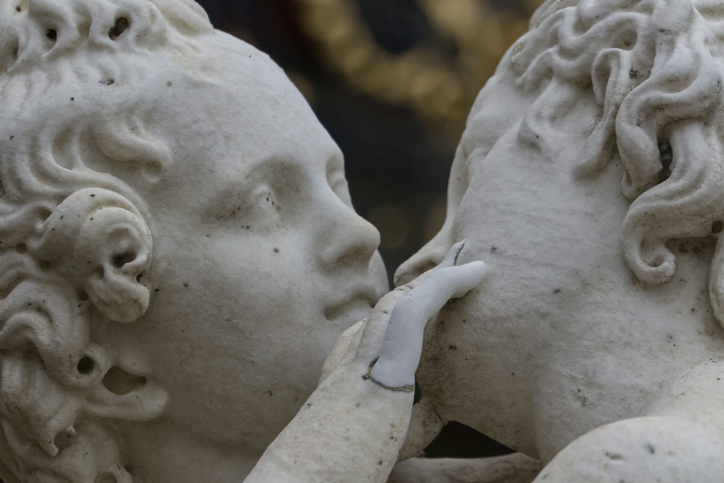 closeup of two white statues, one touching the other