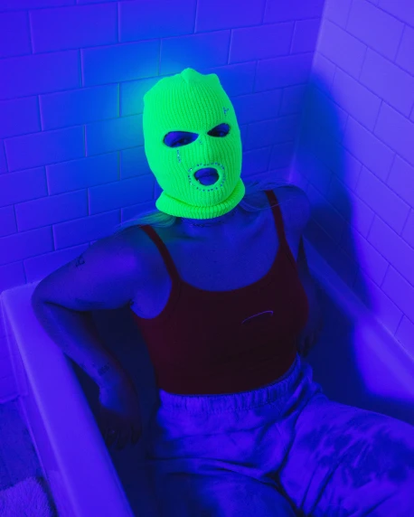 a person wearing a neon green face mask sitting in an illuminated room