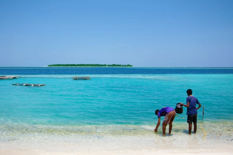 two people that are standing in the sand near the water