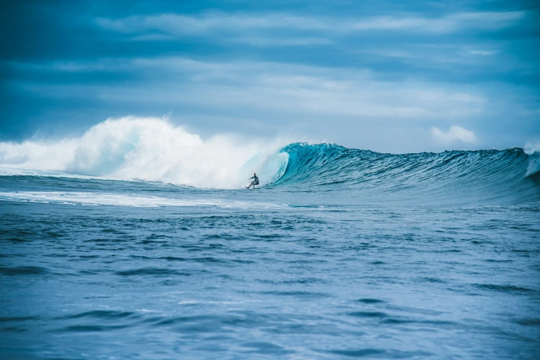 a large ocean wave with one person riding it