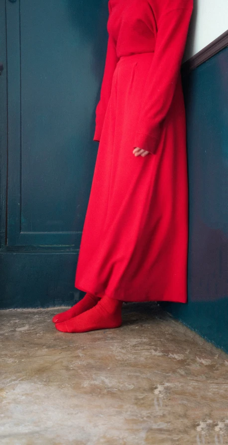 an image of woman standing against wall wearing red