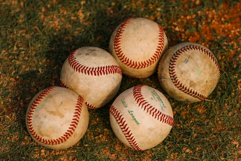 a group of five baseballs on some grass