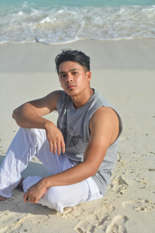 a young man sitting in the sand on the beach