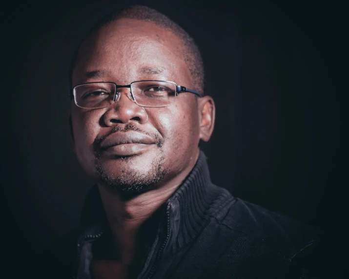 an african american man wearing a glasses and looking forward