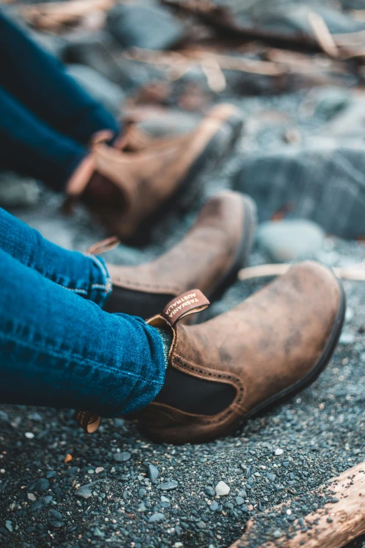 two people sitting on rocks with the feet crossed