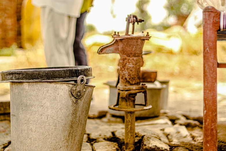 a rusty old machine with old buckets and a man standing nearby