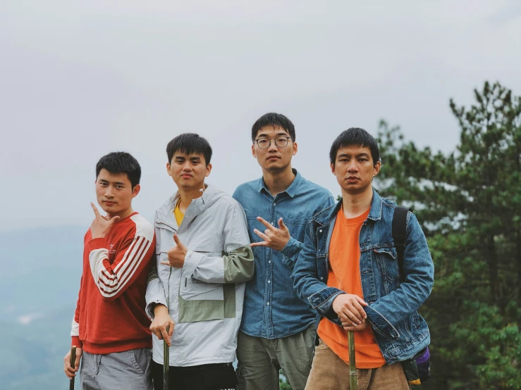 four guys are posing in front of a mountain