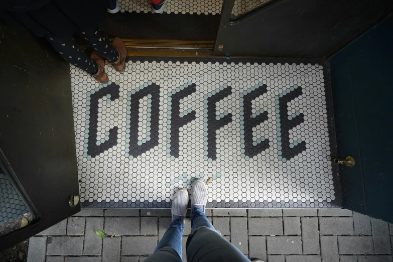 someone standing on a street next to a sign that says coffee