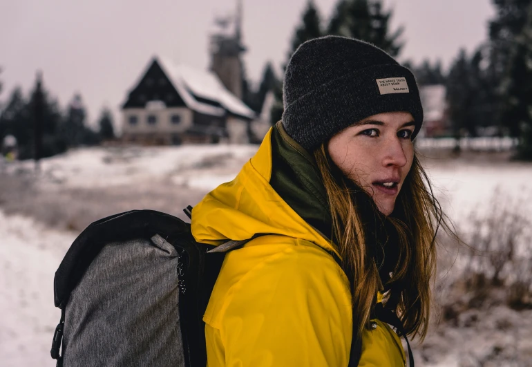 a woman in yellow is wearing a backpack