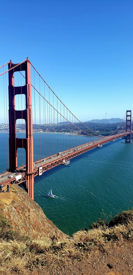 a tall bridge on top of a hill next to water