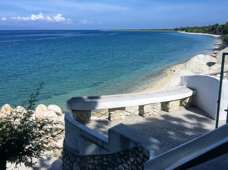 a white bench sitting on the side of a sandy beach