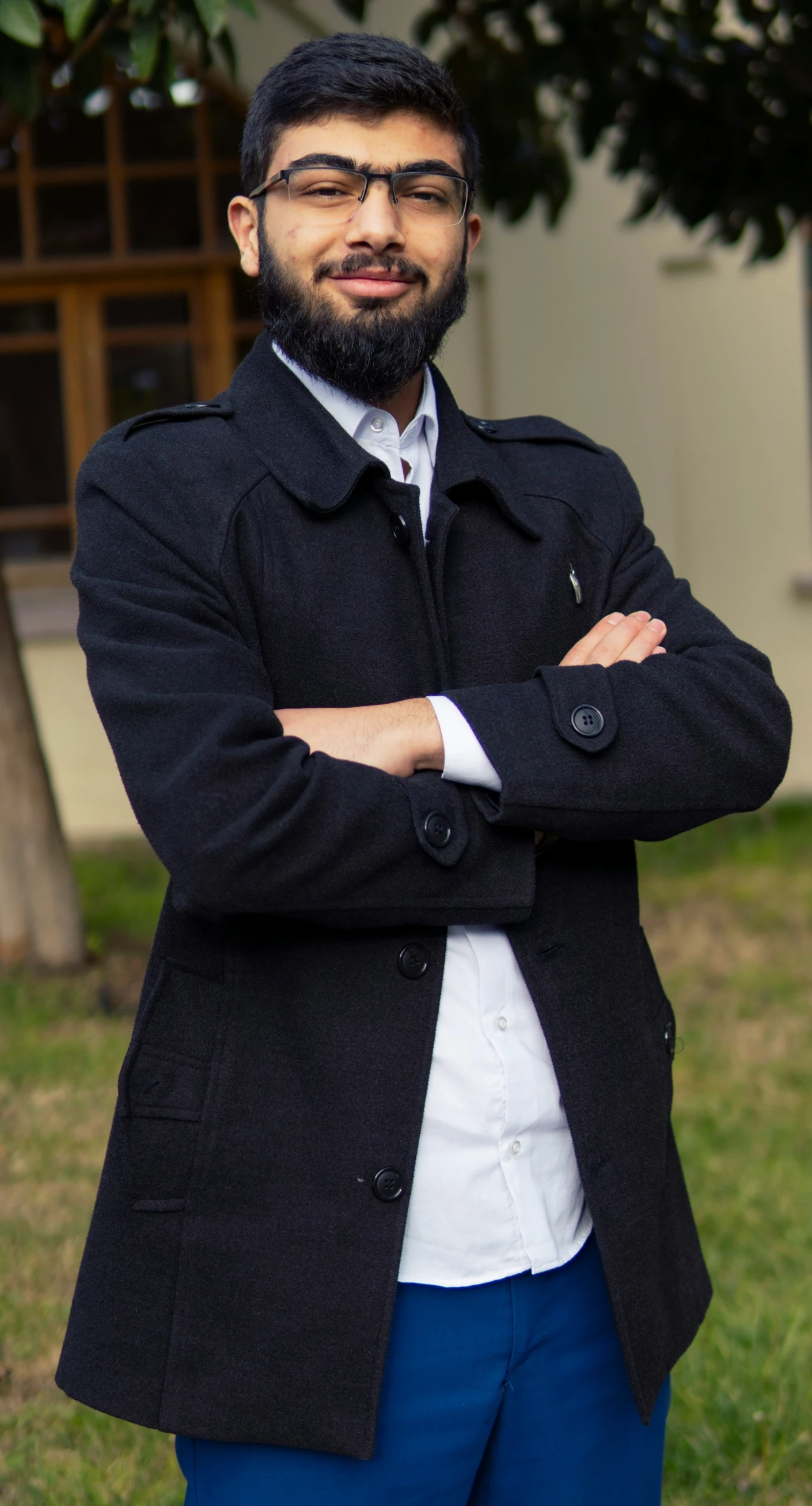 a man with a beard is standing outside with his arms crossed