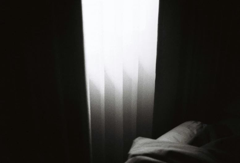 a bed sitting in front of a window next to a light