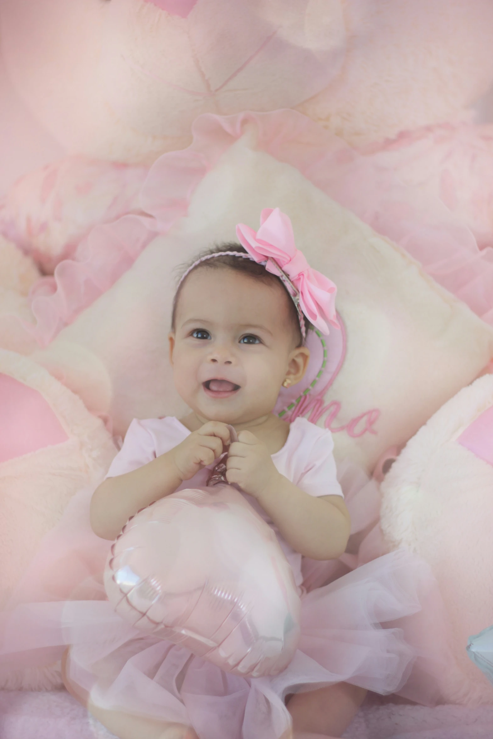 a baby girl dressed in pink sitting on a stuffed animal