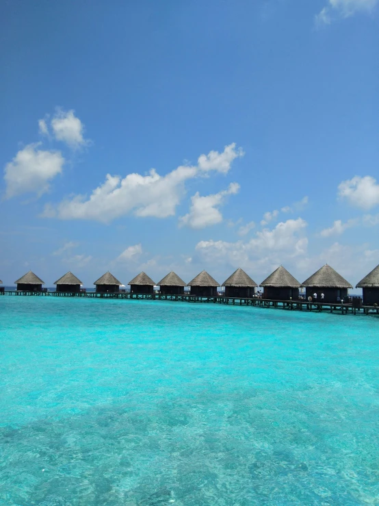 several huts sitting in the ocean next to the beach