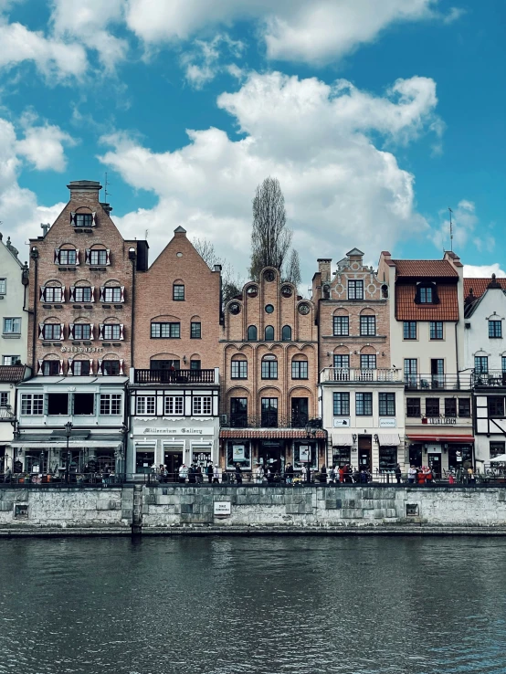 some buildings along the water and people walking by them