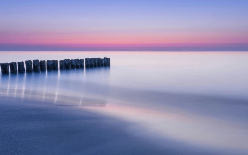 a fence on the beach in the middle of the ocean