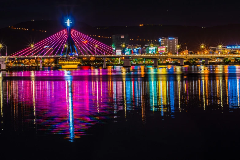 a bridge over water with lights reflecting off the ground