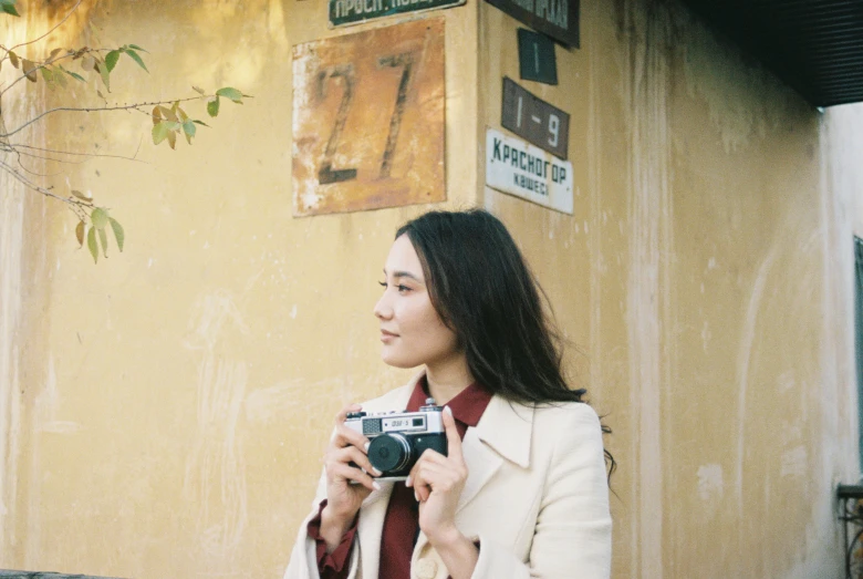 a woman taking a po while standing next to a building