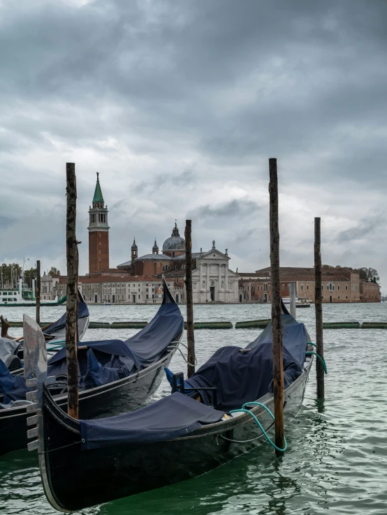 two gondolas tied to poles in water near a castle