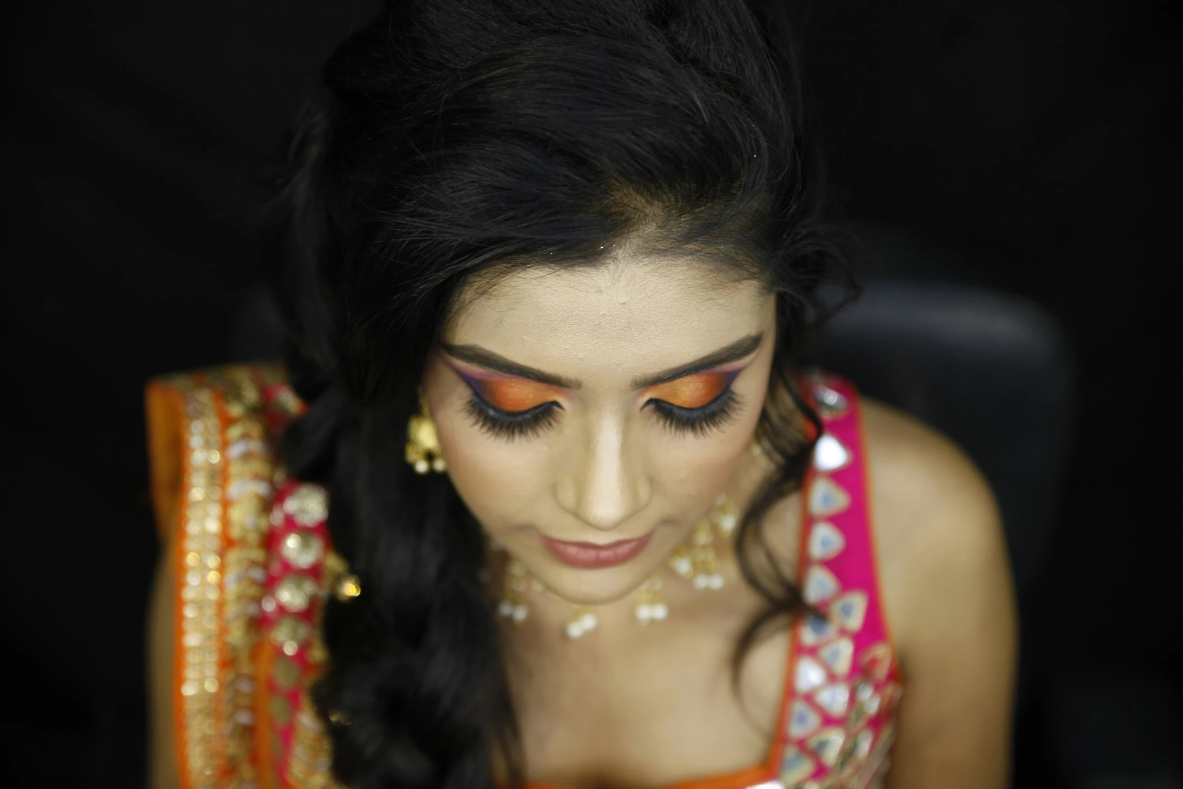 a girl with makeup and traditional indian dress looking down