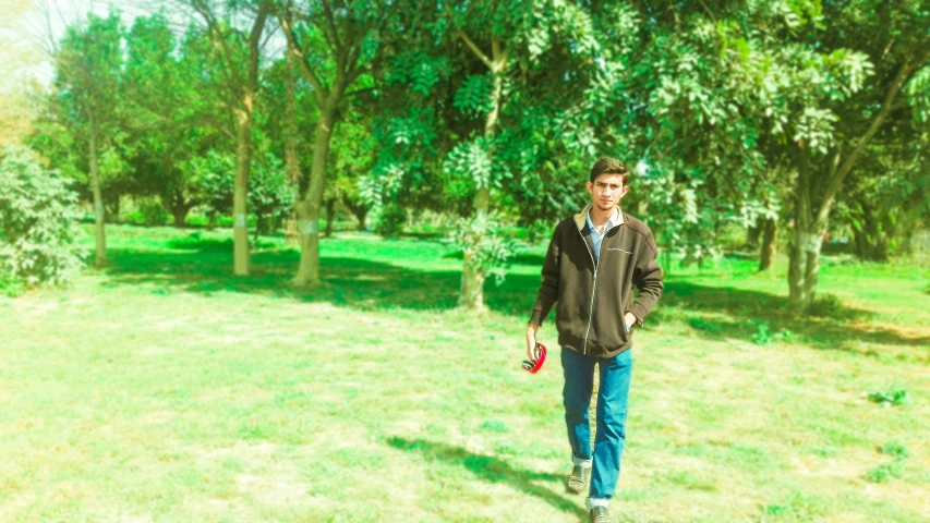 a man walking in an open field near trees