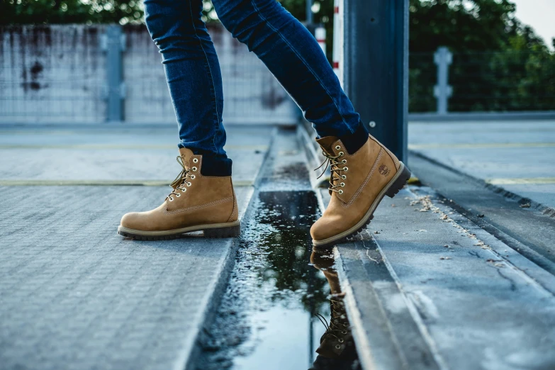 a person wearing brown shoes walking in the rain