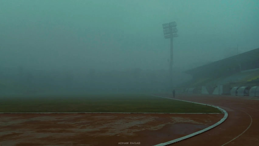 fog is covering a baseball field and green grass