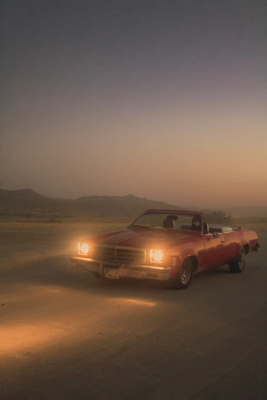 a vintage muscle car driving down the road at night