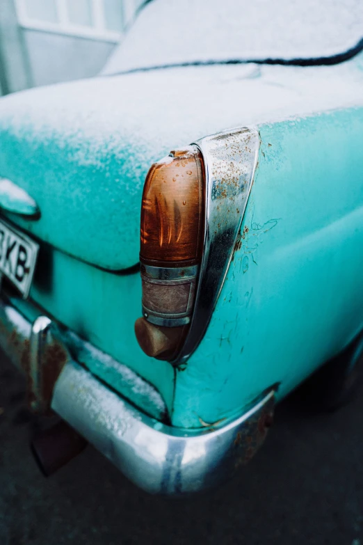 a old rusty, blue car with a shiny rear view mirror